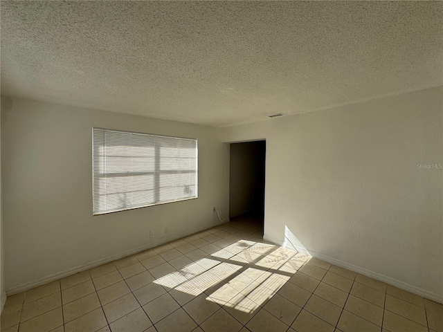 tiled empty room with a textured ceiling