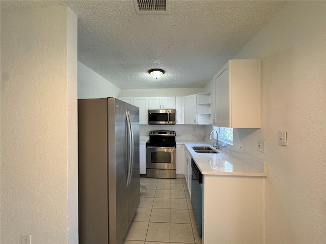 kitchen with white cabinetry, sink, stainless steel appliances, a textured ceiling, and light tile patterned floors