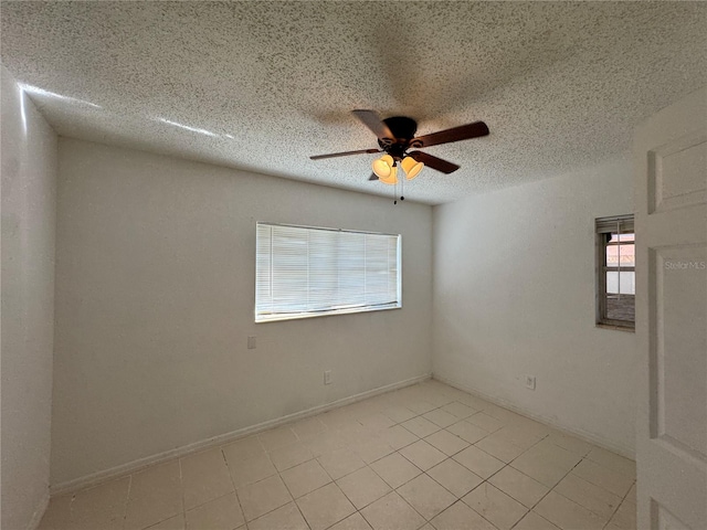 empty room featuring ceiling fan, light tile patterned floors, and a textured ceiling