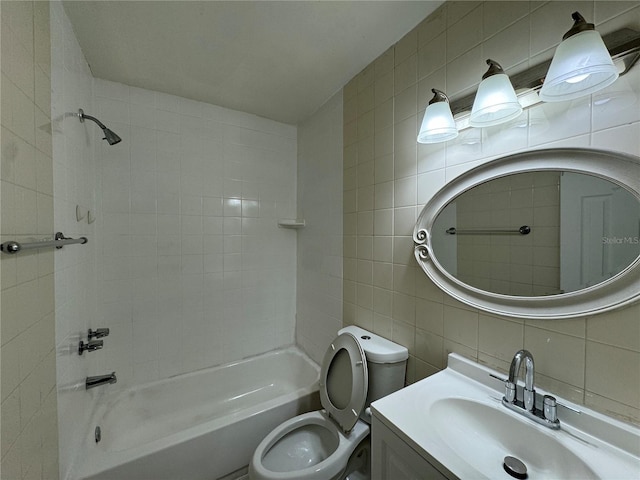 full bathroom with vanity, tiled shower / bath, toilet, tile walls, and tasteful backsplash