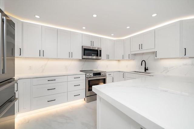 kitchen with decorative backsplash, sink, white cabinetry, and stainless steel appliances