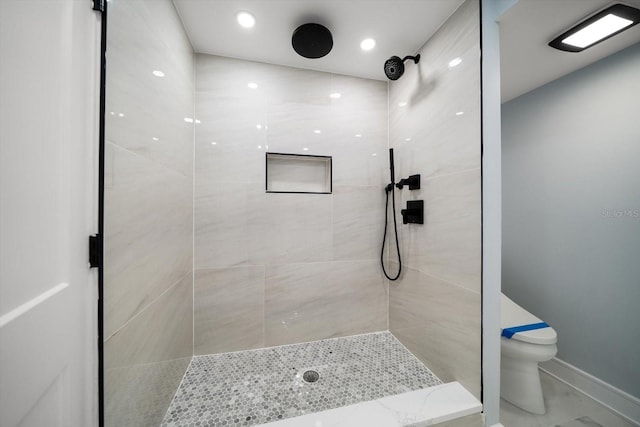 bathroom featuring a tile shower and toilet