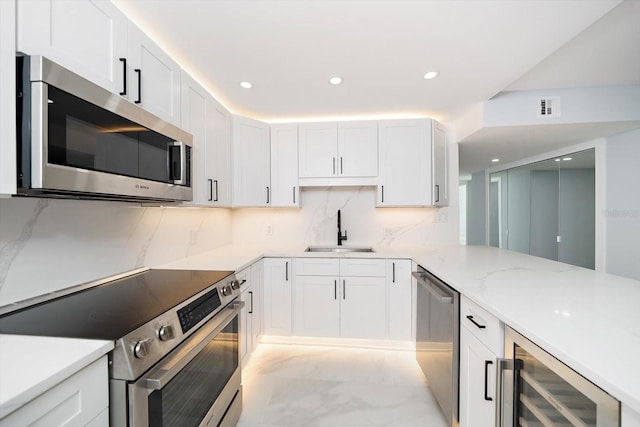 kitchen featuring stainless steel appliances, a sink, wine cooler, recessed lighting, and white cabinetry
