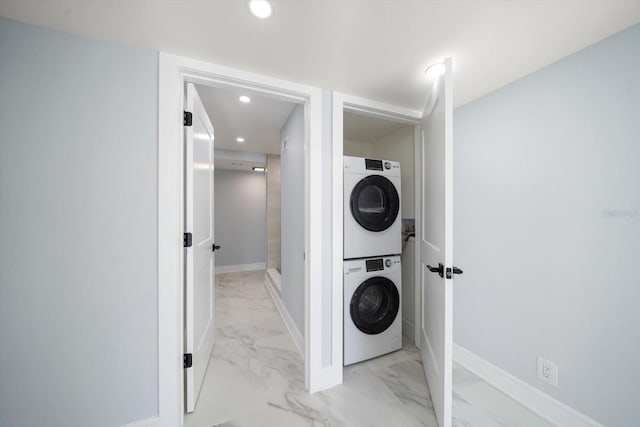 clothes washing area featuring stacked washer and clothes dryer, light marble finish flooring, recessed lighting, and baseboards