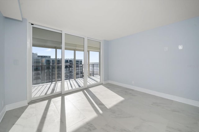 unfurnished room featuring floor to ceiling windows, baseboards, and marble finish flooring