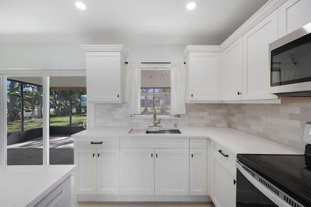 kitchen with white cabinets, decorative backsplash, electric stove, and sink