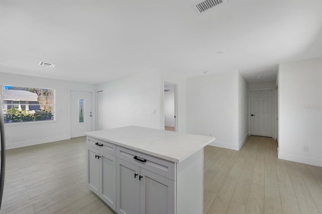 kitchen featuring light stone countertops, a center island, and light hardwood / wood-style flooring