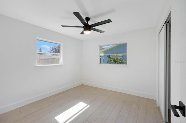 empty room with ceiling fan and light hardwood / wood-style flooring