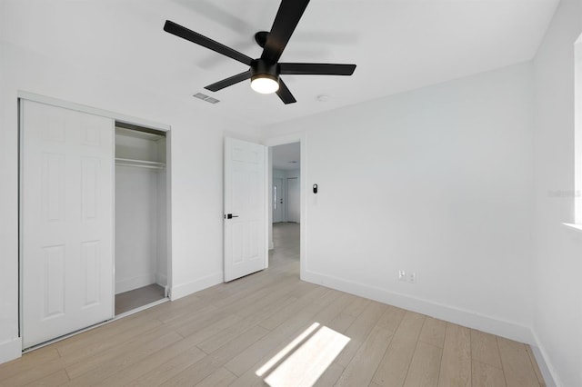 unfurnished bedroom with ceiling fan, light wood-type flooring, and a closet