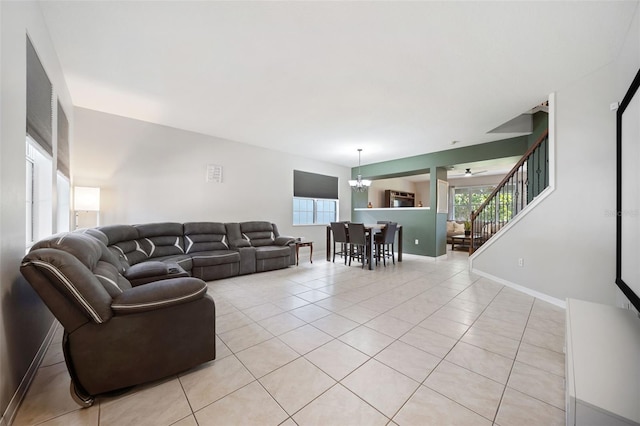 tiled living room with ceiling fan with notable chandelier