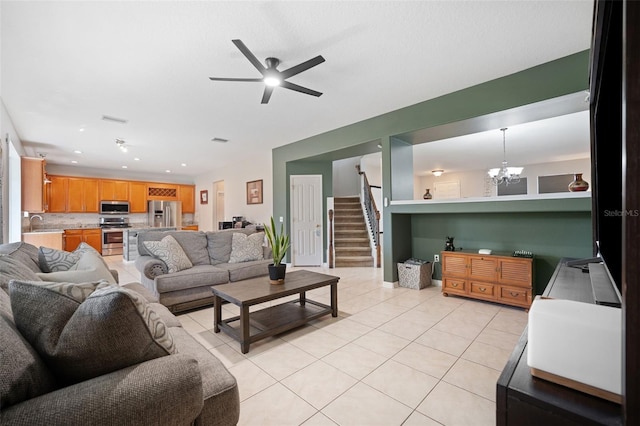 living room featuring sink, light tile patterned floors, and ceiling fan with notable chandelier