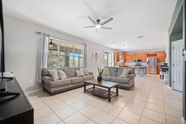 tiled living room with ceiling fan and a textured ceiling