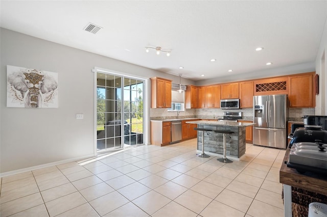 kitchen with pendant lighting, a center island, stainless steel appliances, and light tile patterned flooring