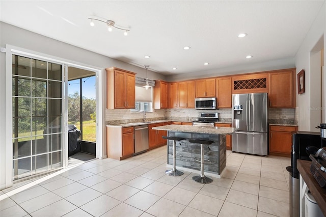 kitchen with pendant lighting, sink, decorative backsplash, light stone counters, and stainless steel appliances