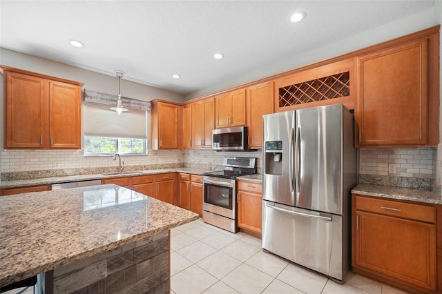 kitchen with pendant lighting, sink, light stone countertops, light tile patterned flooring, and stainless steel appliances