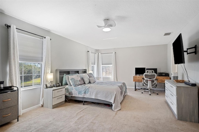 bedroom with a textured ceiling, light colored carpet, and ceiling fan