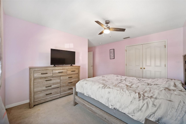 bedroom with ceiling fan, light colored carpet, and a closet