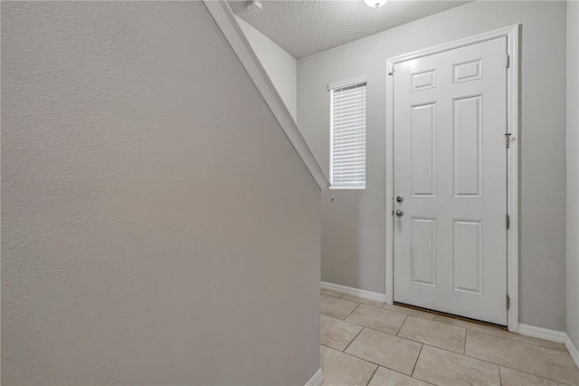 entryway with a textured ceiling and light tile patterned floors