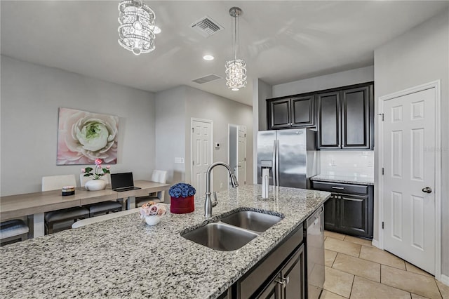 kitchen with sink, stainless steel appliances, tasteful backsplash, light stone countertops, and a chandelier