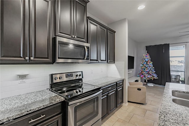 kitchen featuring decorative backsplash, light tile patterned floors, light stone counters, and appliances with stainless steel finishes