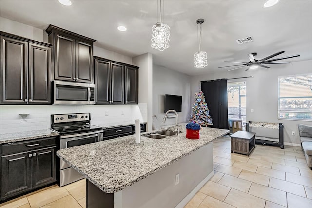 kitchen with decorative light fixtures, decorative backsplash, a kitchen island with sink, appliances with stainless steel finishes, and sink