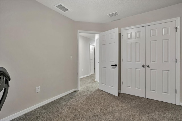 unfurnished bedroom with a textured ceiling, carpet floors, and a closet