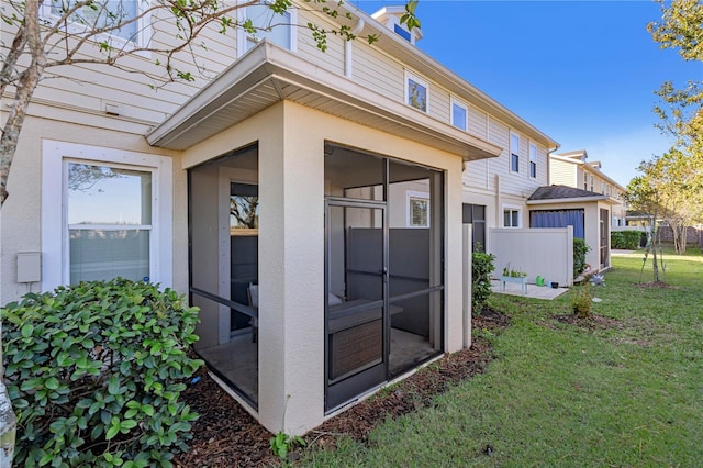 rear view of property with a lawn and a sunroom