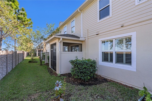 view of home's exterior featuring a sunroom and a lawn