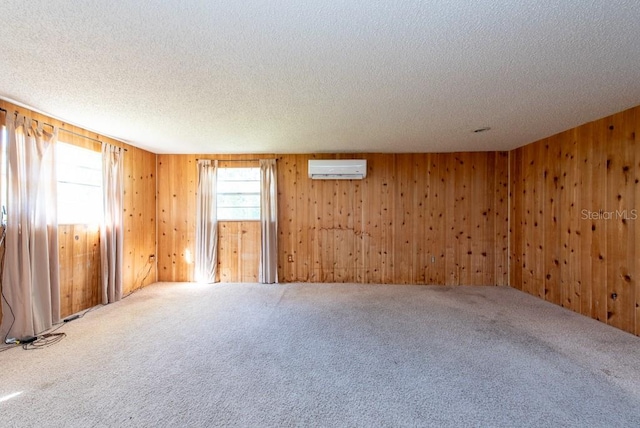 carpeted empty room featuring a textured ceiling, wood walls, and a wall mounted air conditioner