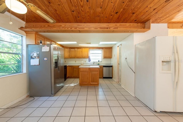 kitchen with plenty of natural light, a center island, light tile patterned floors, and stainless steel appliances