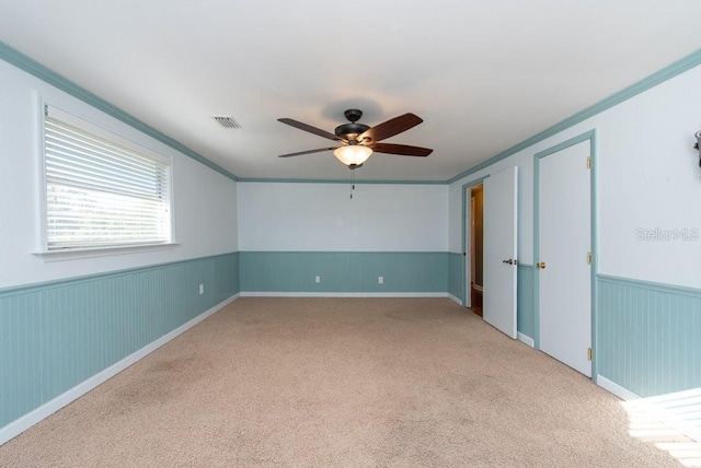 unfurnished room featuring light colored carpet, ceiling fan, and ornamental molding