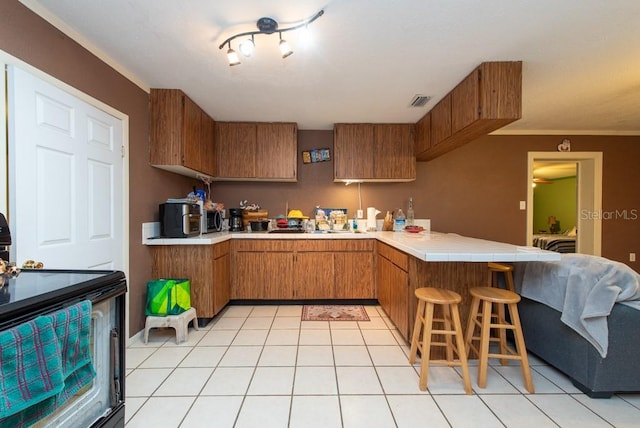 kitchen with kitchen peninsula, ornamental molding, light tile patterned floors, tile countertops, and black electric range