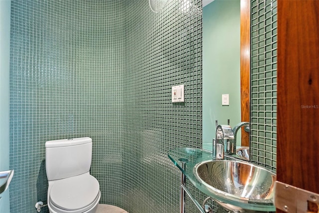 bathroom with sink, tile walls, and toilet