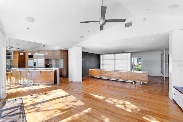 kitchen with stainless steel built in refrigerator, sink, backsplash, ceiling fan, and light wood-type flooring