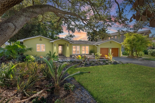 single story home featuring a garage and a yard