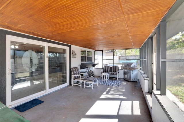 sunroom with ceiling fan and wooden ceiling