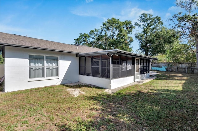 back of house featuring a sunroom and a lawn