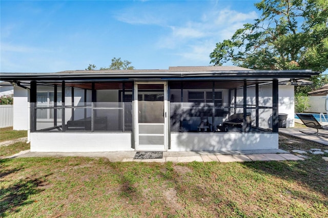 rear view of property featuring a sunroom and a yard