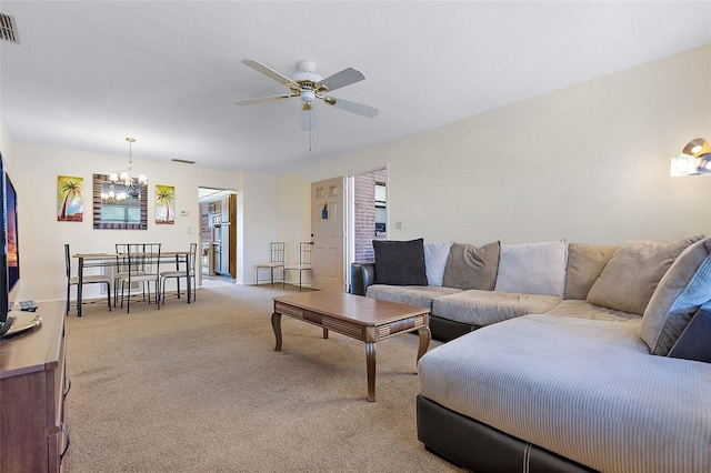 carpeted living room featuring ceiling fan with notable chandelier