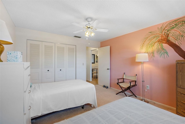 carpeted bedroom featuring ceiling fan, a closet, and a textured ceiling