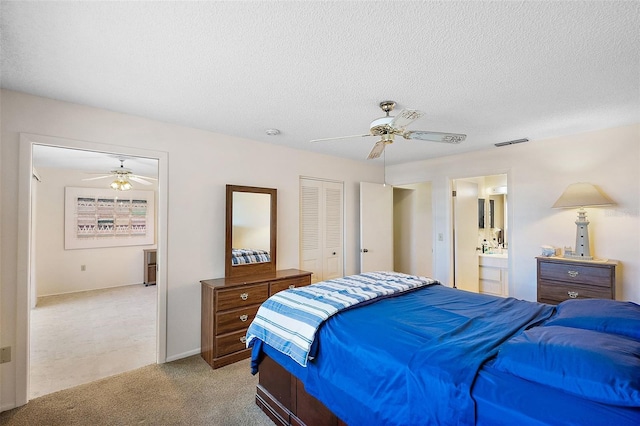 bedroom with light carpet, ensuite bath, a textured ceiling, ceiling fan, and a closet