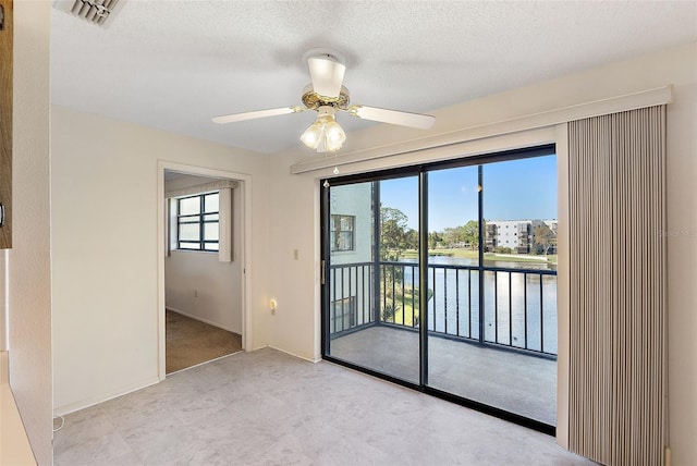 unfurnished room featuring a textured ceiling, a water view, and ceiling fan