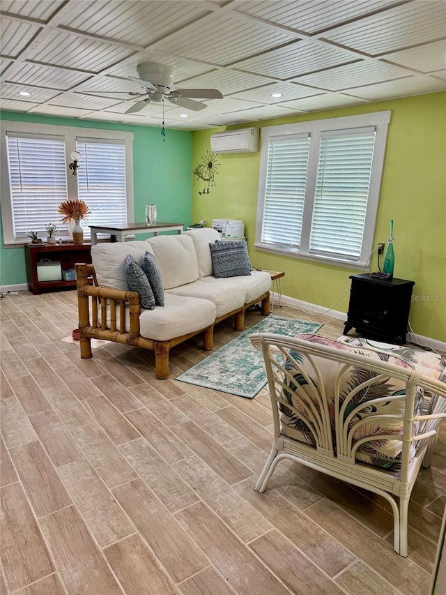 living room featuring a wall mounted air conditioner, ceiling fan, and light hardwood / wood-style floors