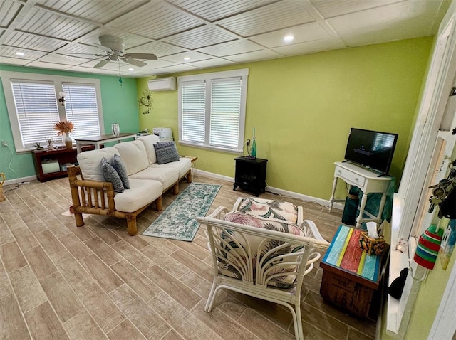 living room with ceiling fan, light wood-type flooring, and an AC wall unit