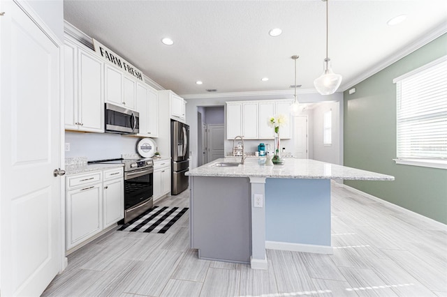 kitchen with appliances with stainless steel finishes, sink, decorative light fixtures, white cabinetry, and an island with sink