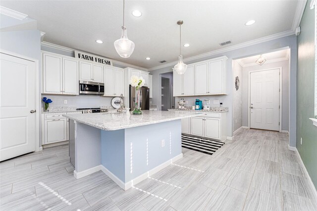 kitchen featuring ornamental molding, stainless steel appliances, pendant lighting, white cabinets, and an island with sink