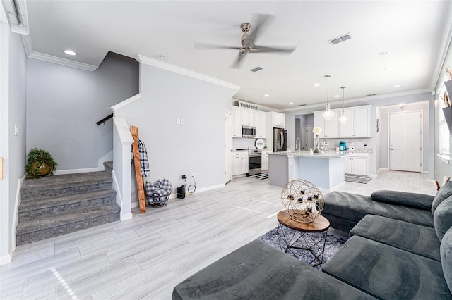 living room with light wood-type flooring, ceiling fan, ornamental molding, and sink