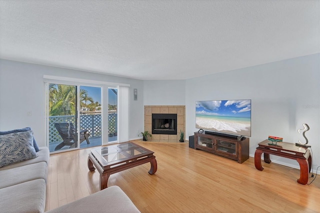 living room with a tile fireplace, wood-type flooring, and a textured ceiling