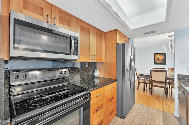 kitchen with an inviting chandelier, decorative backsplash, light wood-type flooring, a textured ceiling, and stainless steel appliances