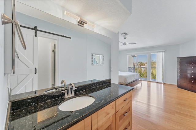 bathroom with vanity, wood-type flooring, a textured ceiling, and ceiling fan